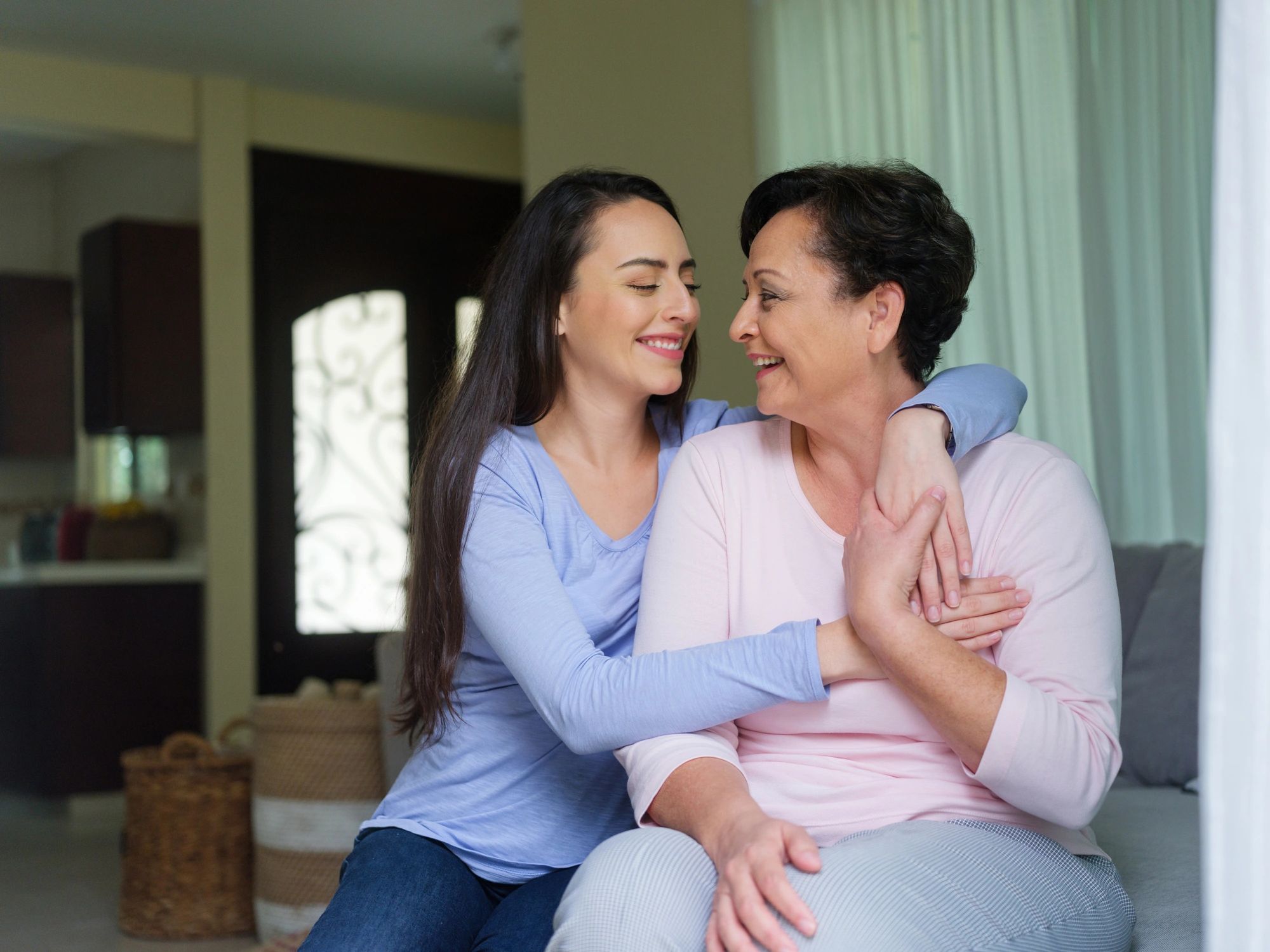 Adult daughter embracing her older mother at home