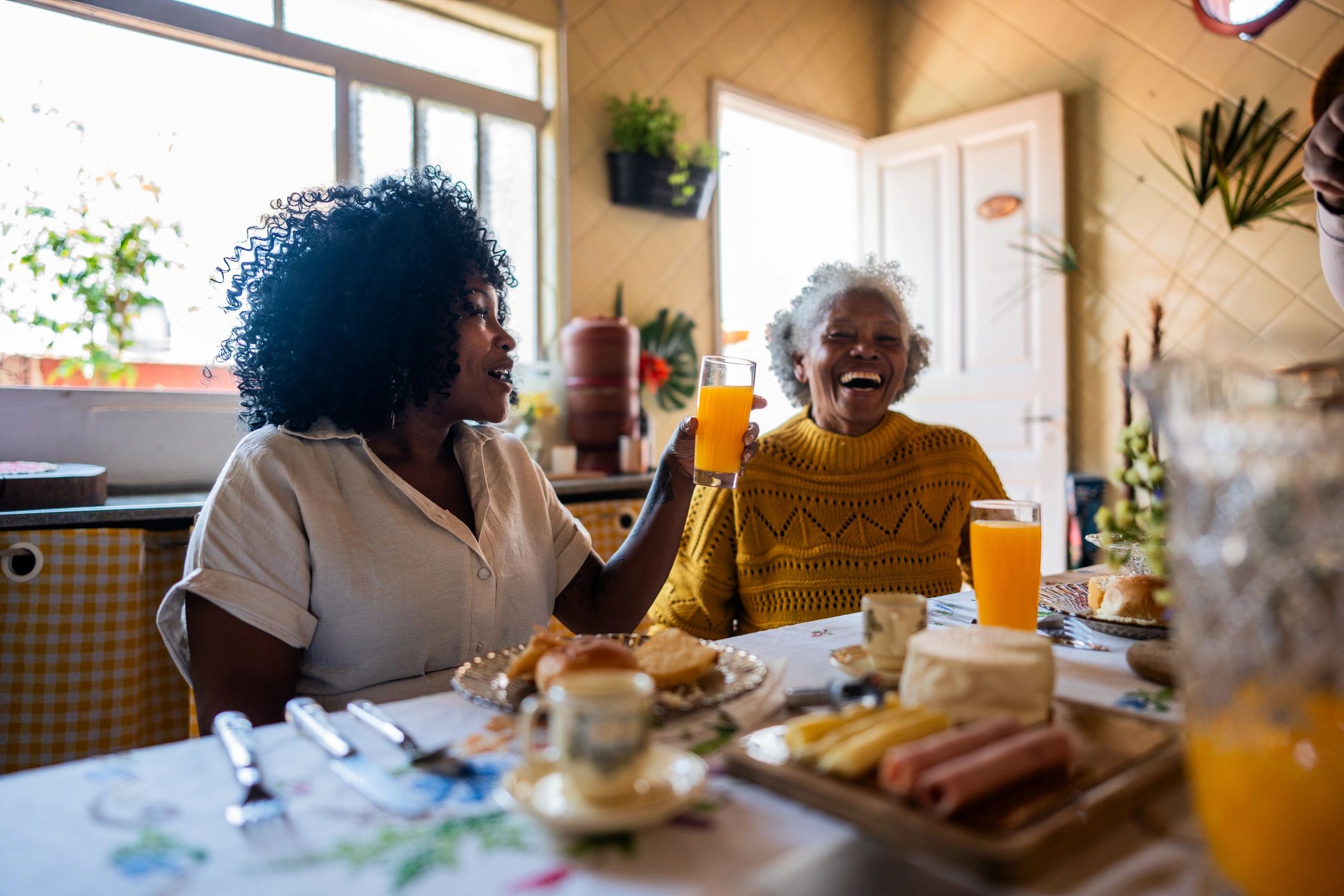 Adult daughter talking with her mother over breakfast at home