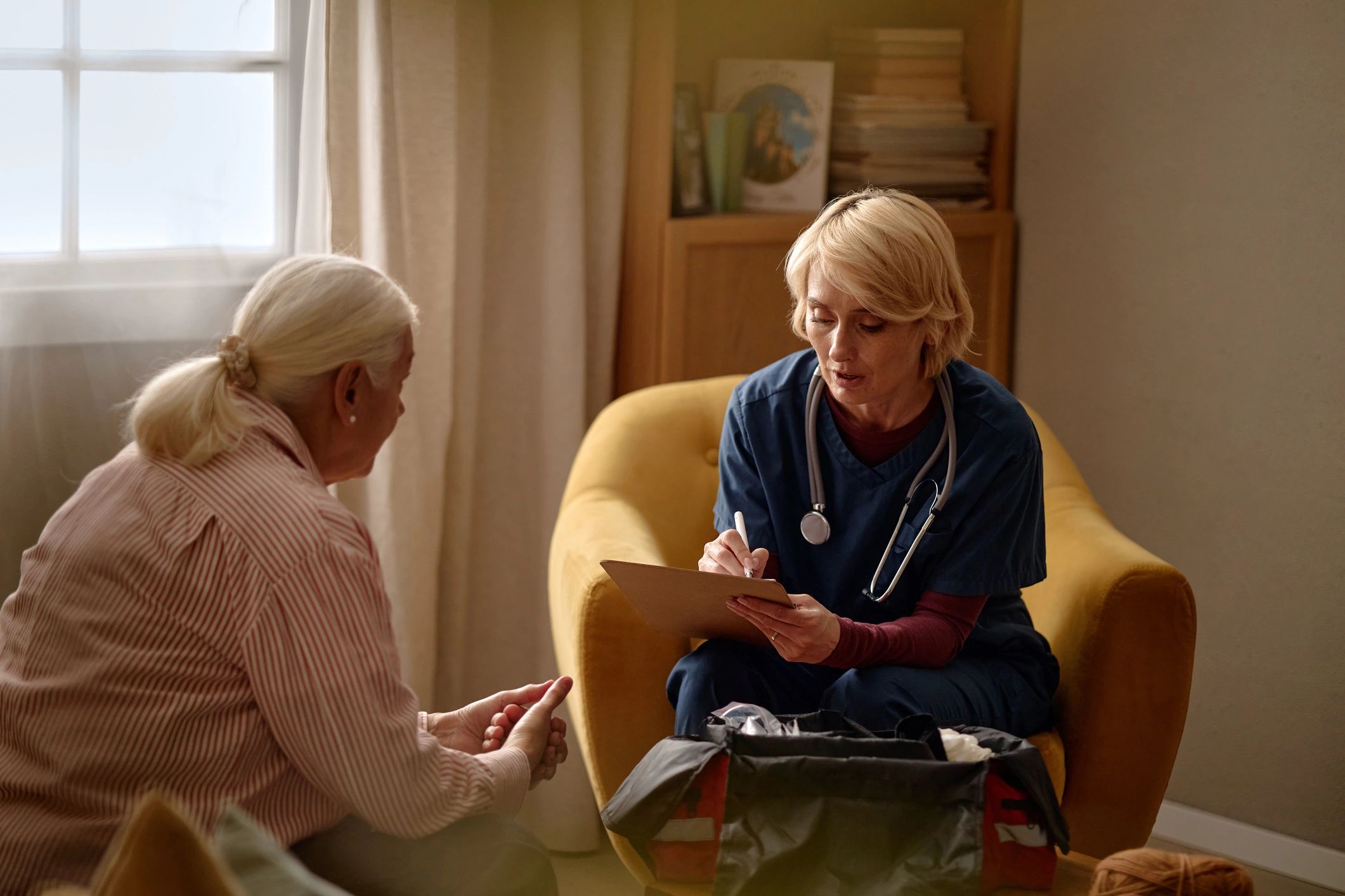 Older woman talking with a caregiver at home in a living room